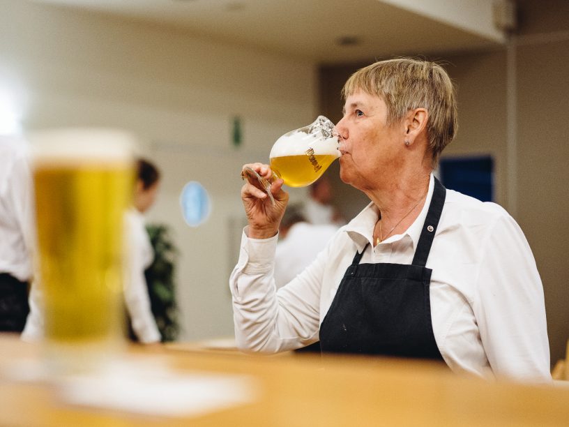 Een cursiste Sommelier proeft van een glas bier.