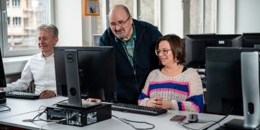 Een leerkracht geeft uitleg aan een cursist aan de computer